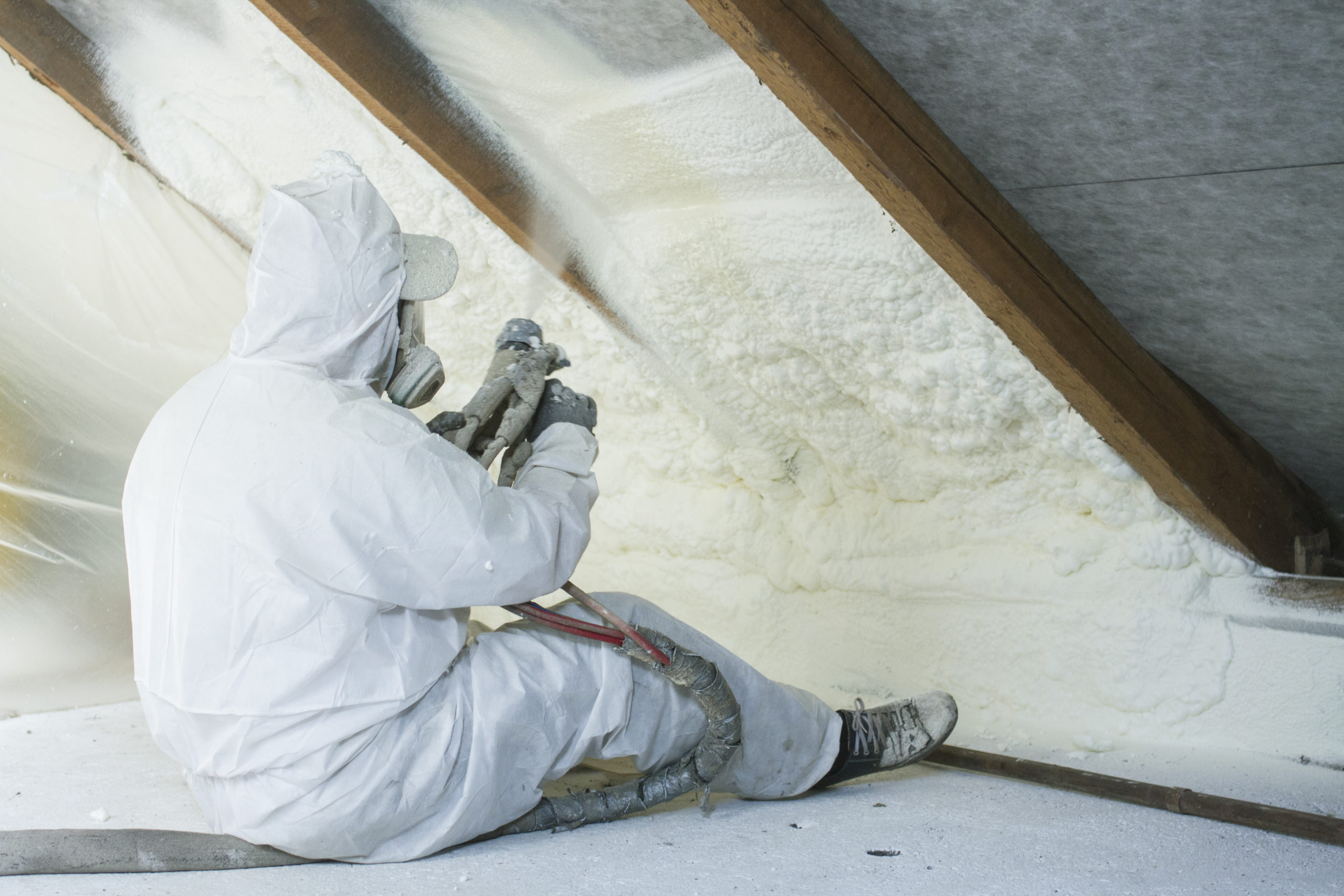 technician spraying foam insulation using plural component gun for polyurethane foam