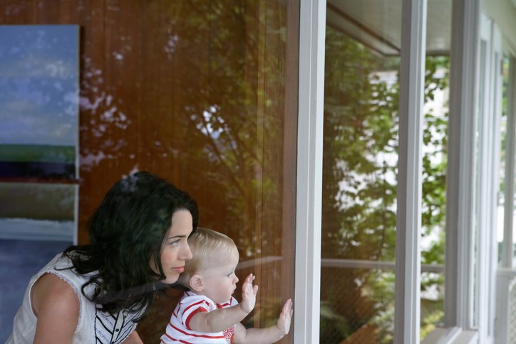 mom and baby looking out a large window together