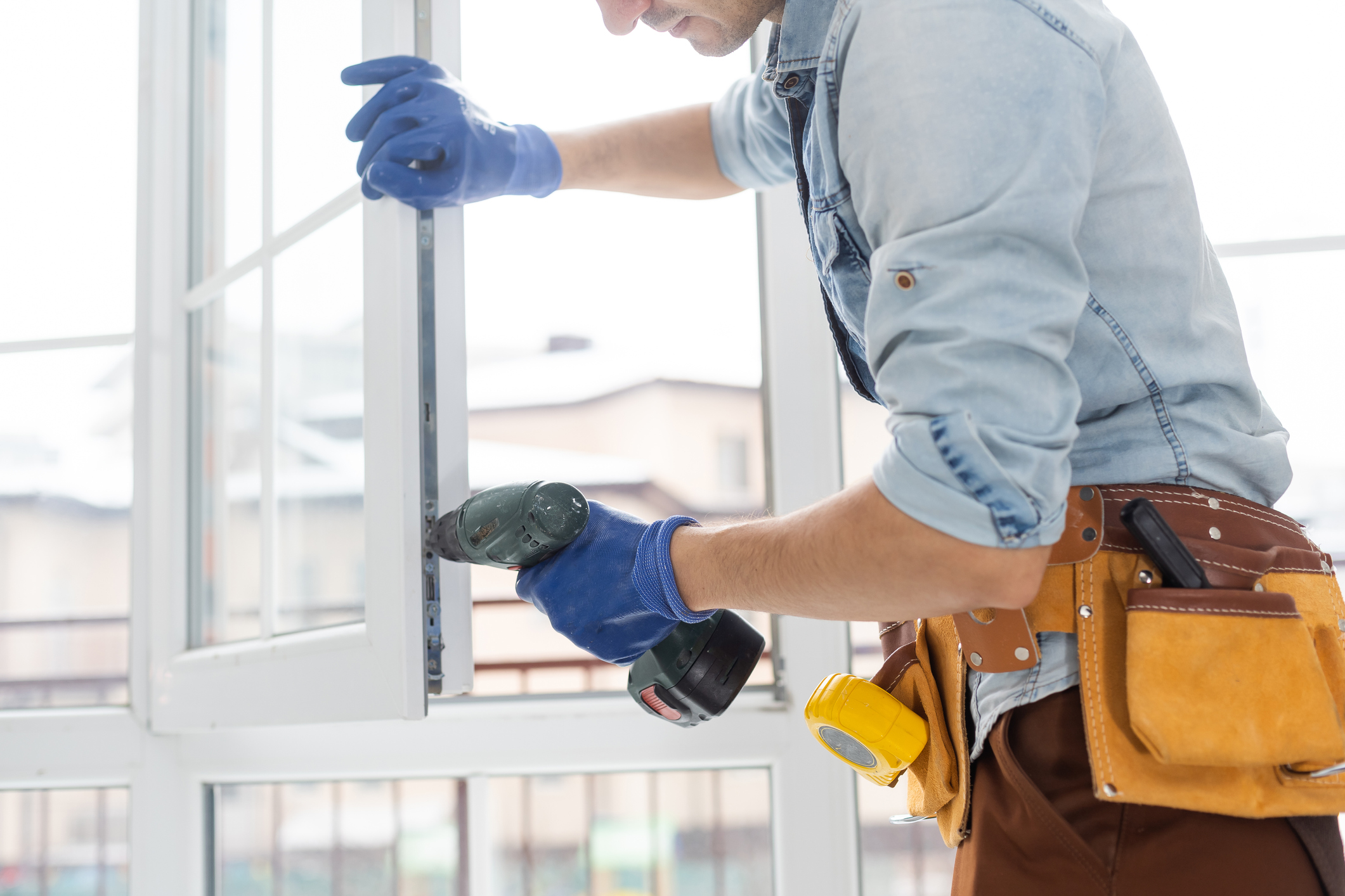 Contractor using a drill to install a window