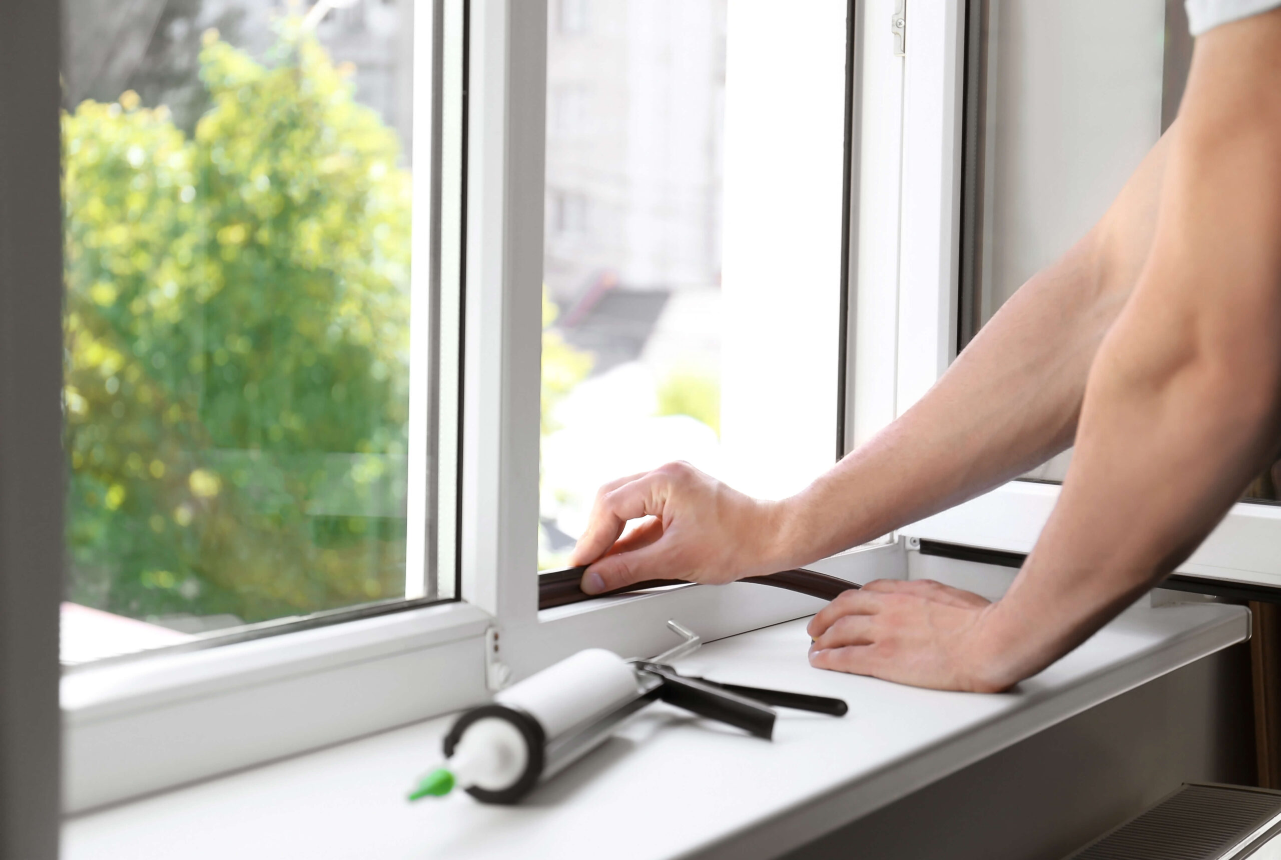 Person putting insulation along the bottom of a window.