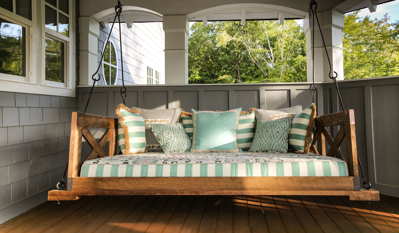 A large bed swing with many pillows in teal and striped teal colors.