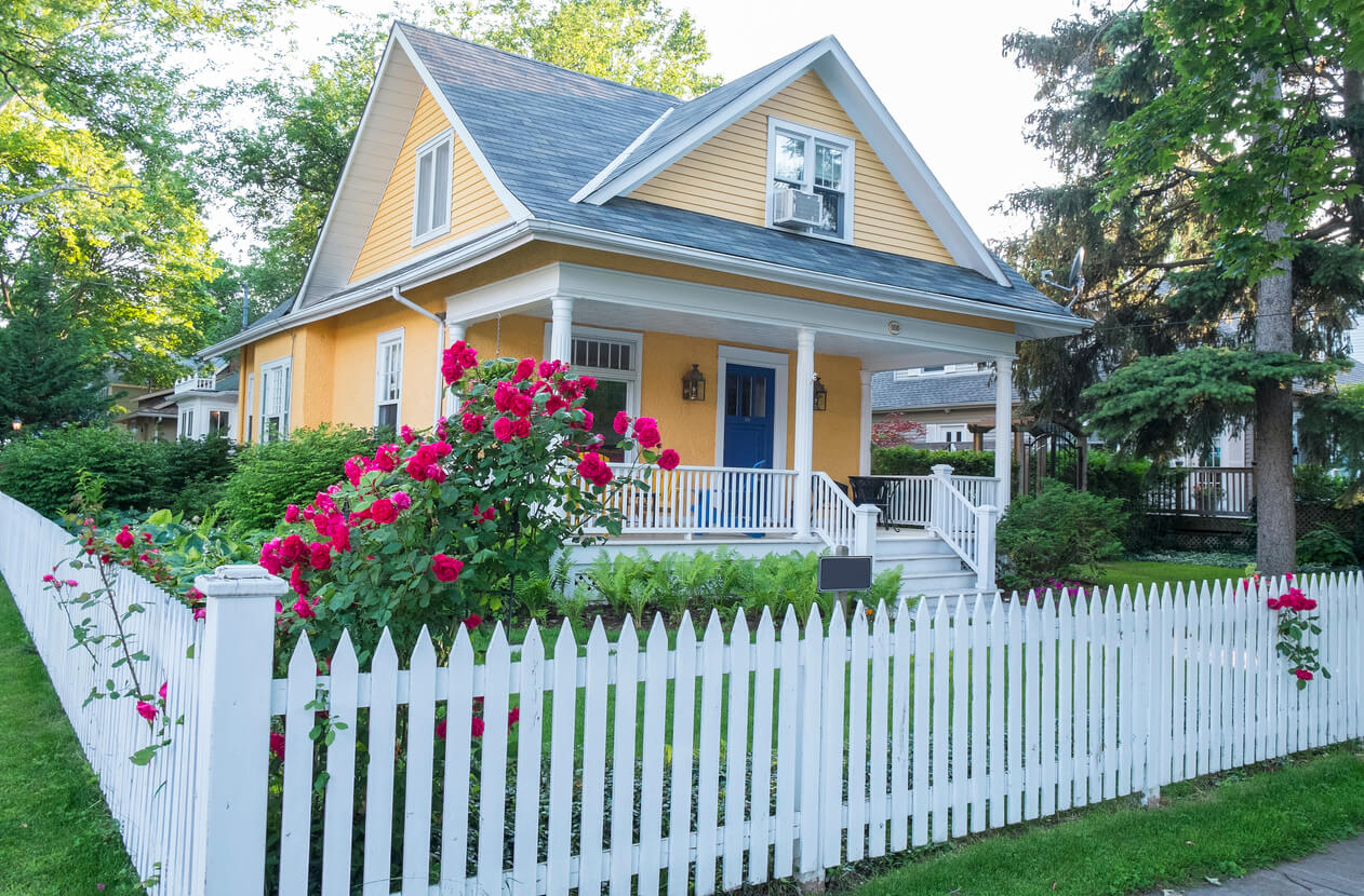 Beautiful yellow house with a white picket fence surrounding it