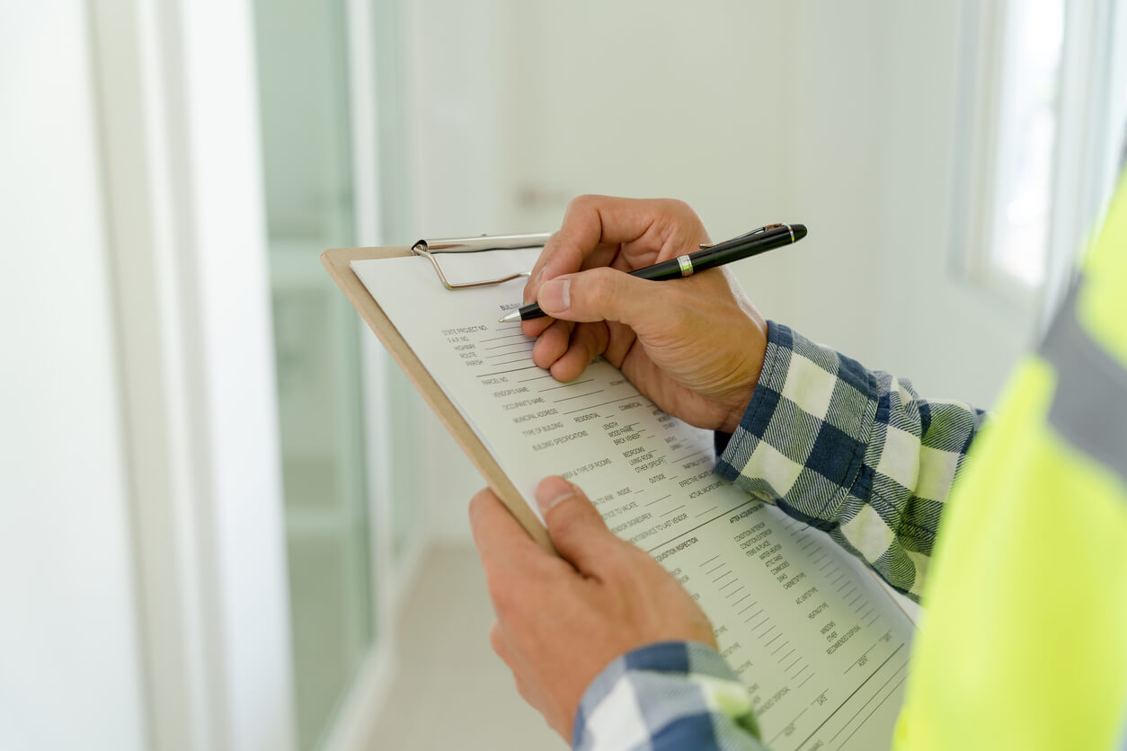 Person reviewing and marking a home inspection checklist