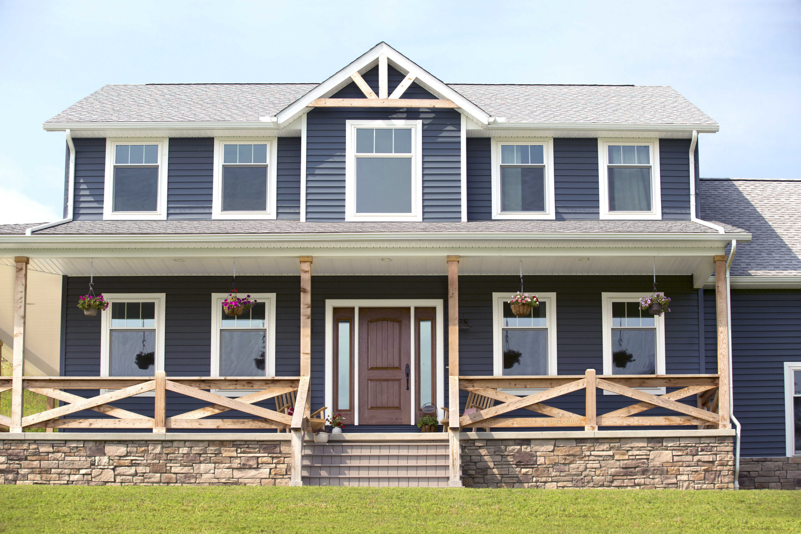 exterior of a large 2 story home with blue siding and rustic wood crossed patio railing