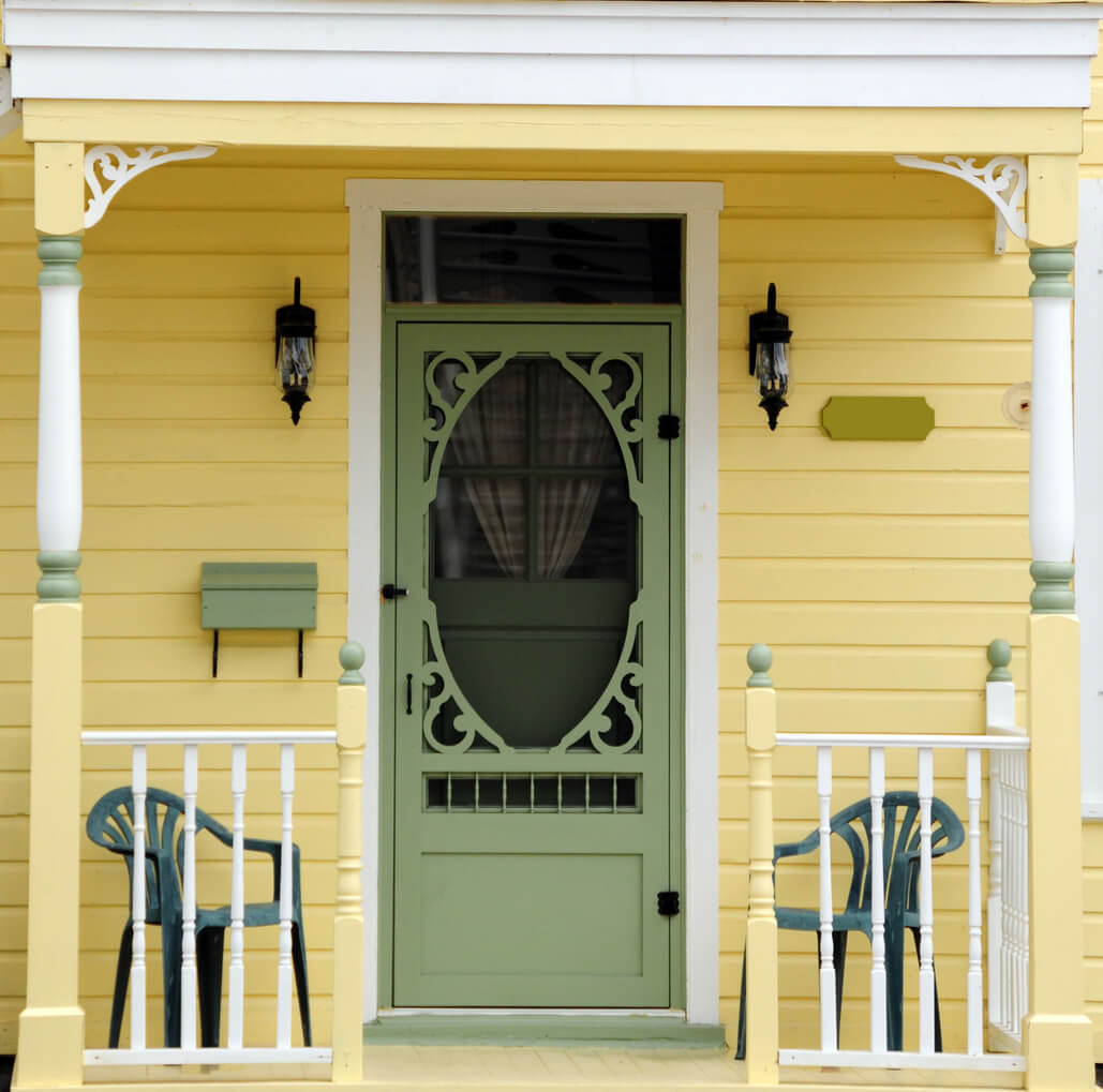 decorative green screen door on a yellow home