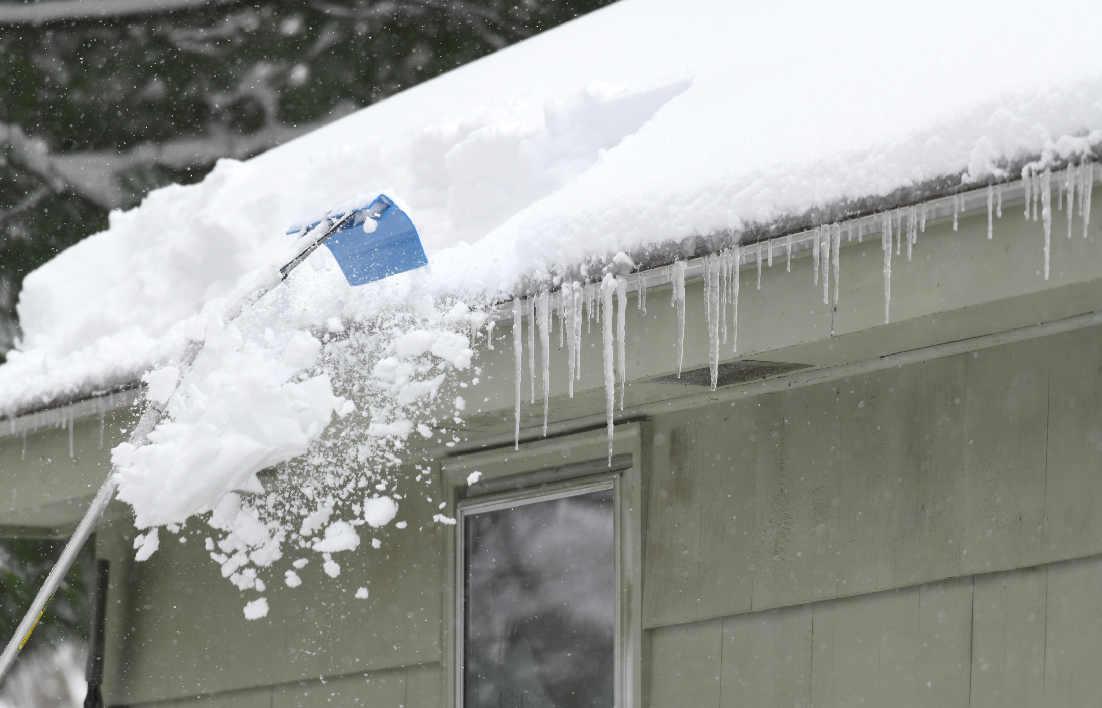 removing snow on the roof using a raking tool