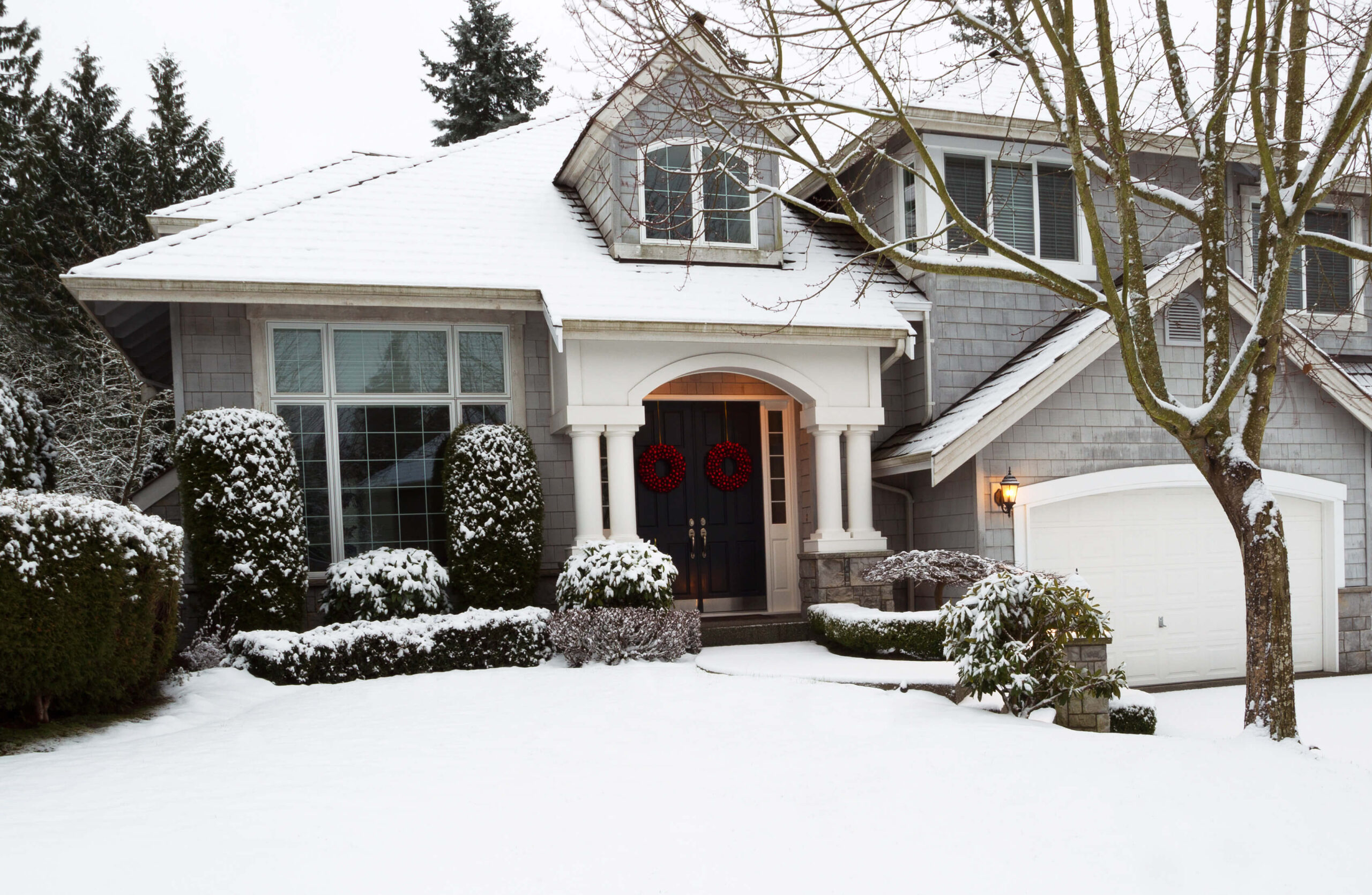 a large home in the winter with snow covering the front yard and roof.